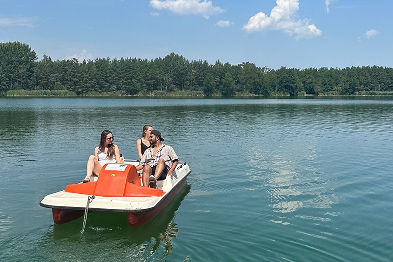 Studierende sitzen auf einem Steg am See