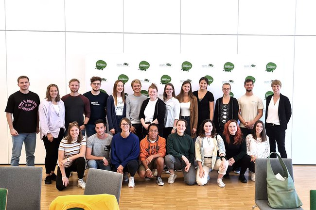 Auf dem Gruppenbild sieht man Studierende des Studiengangs Physiotherapie, die erste Reihe kniend und die zweite Reihe stehend. Rechts außen in der zweite Reihe steht Barbara Wondrasch. Im Hintergrund befindet sich eine Sponsorenwand von Harbach.