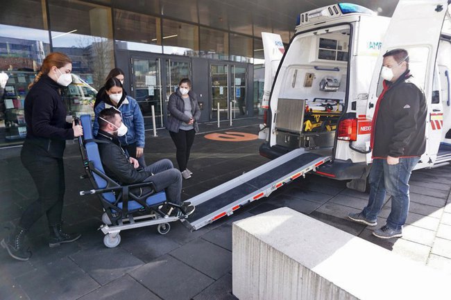 Studierende bei einer Übung: Sie schieben eine Person im Rollstuhl über eine Schieberampe in einen bereitstehenden Transporter