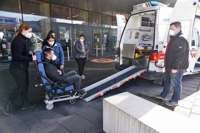 Studierende bei einer Übung: Sie schieben eine Person im Rollstuhl über eine Schieberampe in einen bereitstehenden Transporter