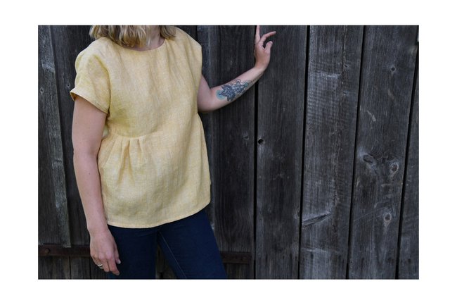 ELISIA - Nachhaltige Designs genäht in Sankt Pölten Model in gelbem Shirt vor Holzwand