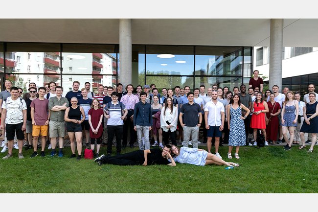 Eine große Gruppe von lächelnden Studierenden (ca. 60 Personen) auf der Wiese vor der FH St. Pölten